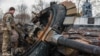 Український військовослужбовець оглядає залишки знищеного російського танка у нещодавно звільненому селі Лук'янівка Київської області, 27 березня 2022 року