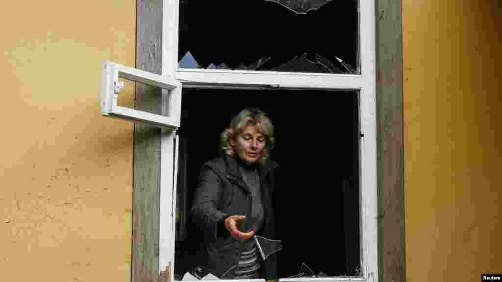 52-летняя Валентина Петренко смотрит из разбитого взрывной волной окна своего дома в поселке Дружба, расположенном неподалеку от складов боеприпасов.