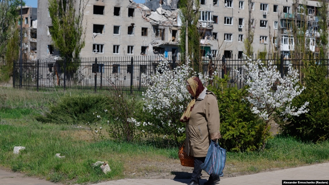 Žena tokom proslave pravoslavnog Uskrsa, dok se u pozadini vidi stambena zgrada oštećena tokom rusko-ukrajinskog sukoba, u Avdijevki, u oblasti Donjeck, oblast Ukrajine pod ruskom kontrolom, 20. aprila 2025. 